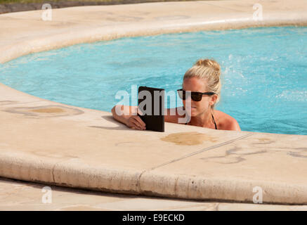 Frau liest einen Kindle in einem Schwimmbad im Urlaub, Mauritius Stockfoto