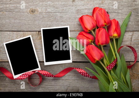 Frische Tulpen und leere Bilderrahmen über Holztisch Hintergrund Stockfoto