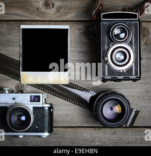 Vintage-Kamera mit objektiven und leere altes Foto auf Holz Hintergrund Stockfoto