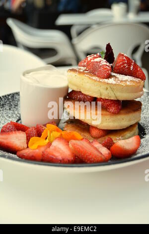 Frühstück mit Pfannkuchen, frische Sahne und Erdbeeren mit einem gemischten weißen Hintergrund. Stockfoto