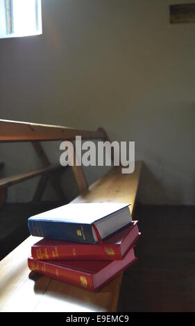 Ein Stapel Bücher auf eine kirchliche Bank lichtdurchflutet Stockfoto