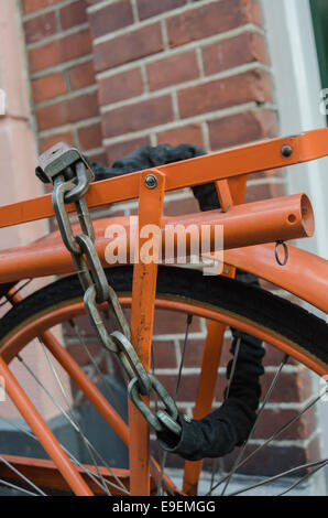 Eine dicke Kette sichert eine orange Fahrrad in den Niederlanden Stockfoto