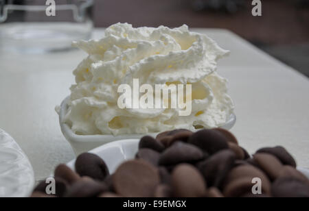 Frische heißer Schokolade wird mit einer separaten Schüssel dick Schlagsahne serviert. Stockfoto