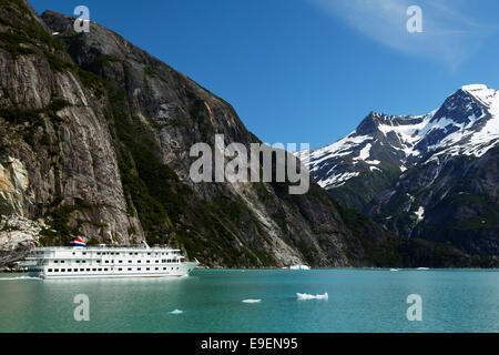 Sheer-von Mauern umgebenen Berge erheben sich über einem kleinen Kreuzfahrtschiff auf Tracy Arm, südöstlichen Alaska, USA Stockfoto