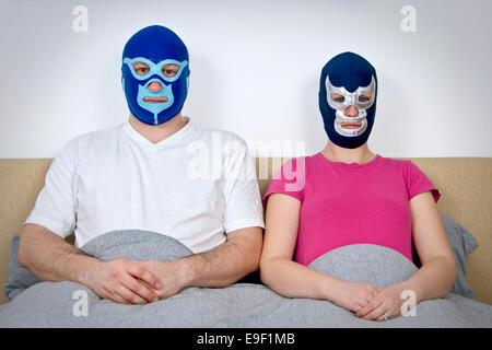 eine lustige Mann und Frau paar sitzen im Bett tragen mexikanischen wrestling / Lucha Libre Masken in diesem humorvollen Komödie Bild Stockfoto
