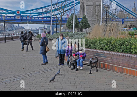 Asiatische Familie füttern Tauben in der Nähe von Tower Bridge, London, England, UK. Stockfoto