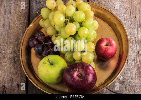 Herbsternte. Nahaufnahme von frischen Bio-Obst auf gelbe Metall Kupfertablett, Äpfel und Trauben auf dem Holztisch Stockfoto