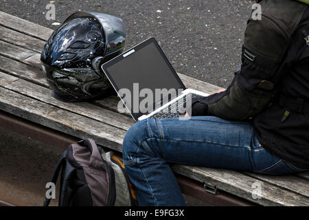 Frau sitzt auf Sitzbank mit einem laptop Stockfoto