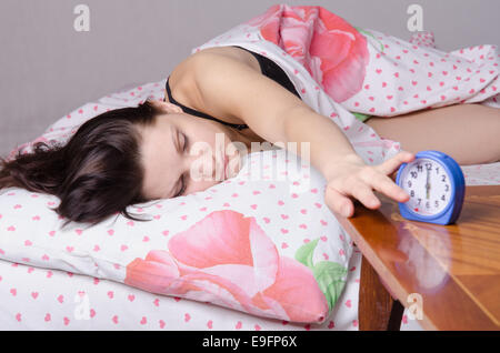 Frau schlafend im Bett, neben einen Wecker auf dem Tisch, die Plätze an den 06:00 Stockfoto