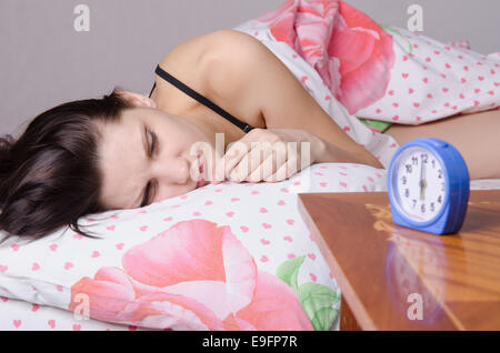 Frau schlafend im Bett, neben einen Wecker auf dem Tisch, die Plätze an den 06:00 Stockfoto