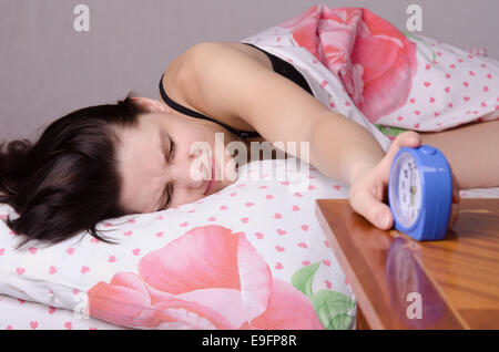 Frau schlafend im Bett, neben einen Wecker auf dem Tisch, die Plätze an den 06:00 Stockfoto