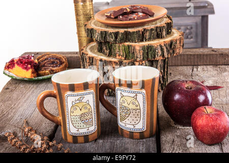 zwei leere Becher für Tee auf Retro-Tisch aus Holz neben der Rinde eines Baumes mit einem roten Äpfel neben Stockfoto