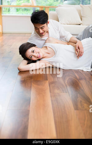 Fröhliches junges Paar liegen auf Holzboden Stockfoto