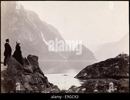 Ein Foto aus dem Jahr 1882, aufgenommen in Hardanger, Norwegen, mit einem Blick auf Odda. Von Axel Lindahl erobert, zeigt es eine Landschaft mit Männern und Frauen, die die natürliche Schönheit und soziale Umgebung der Gegend im späten 19. Jahrhundert repräsentiert. Stockfoto