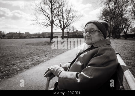 Neunzig Jahre alte Dame sitzt auf der Parkbank im Herbst. England. UK Stockfoto