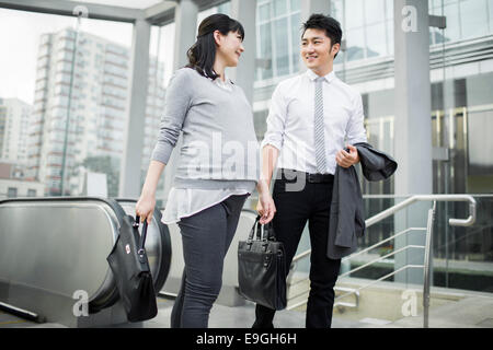 Schwanger Geschäftsfrau im Gespräch mit Kollegen an Spitze der Rolltreppe Stockfoto