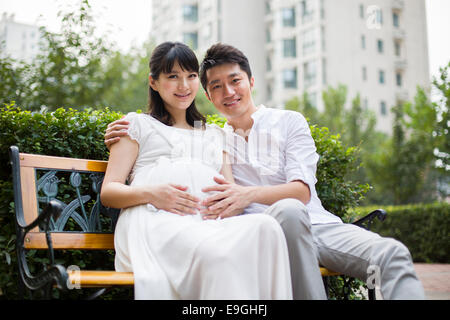 Schwangere Frau und ihr Mann sitzen auf Bank Stockfoto