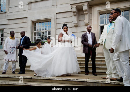 Hackney Rathaus. Standesamt Hochzeit. Braut tragen weiße über einzugeben, mit jungen Brautjungfer ihr Zug halten. Stockfoto
