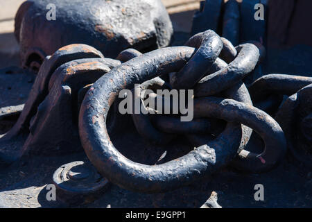 Ein Haufen von sonnenbeschienenen rostige Ketten von einigen Eisenbahnmaterial. Minimalistische Fotografie von einem metallischen Gegenstand Stockfoto