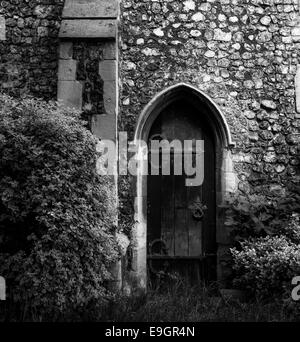 Eine kleine Holztür in der Seite einer mittelalterlichen Kirche. Stockfoto