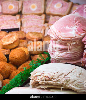 In Scheiben geschnittene Fleisch und eine Auswahl an verschiedenen lokalen Produkten auf dem Display in der Fleischtheke bei einem Metzger oder Feinkost Stockfoto