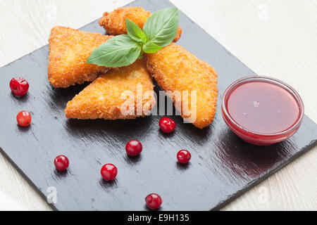 Gebratene Käse-Sticks, serviert mit Preiselbeeren, Sauce auf schwarzem Stein Stockfoto