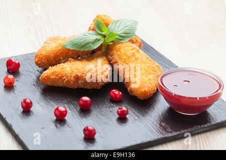 Gebratene Käse-Sticks, serviert mit Preiselbeeren, Sauce auf schwarzem Stein Stockfoto