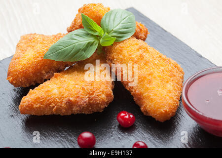 Gebratene Käse-Sticks, serviert mit Preiselbeeren, Sauce auf schwarzem Stein Stockfoto