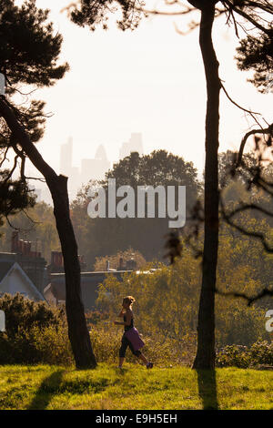 Hampstead Heath, London, UK. 28. Oktober 2014. Ein Läufer auf Hampstead Heath genießt die frühen Morgensonne. Bildnachweis: Paul Davey/Alamy Live-Nachrichten Stockfoto