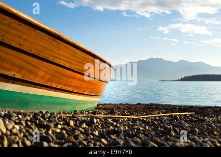 Niedrigen Perspektive einer Jolle auf Stein Strand mit Blick auf den See zu den Bayerischen Alpen, Chiemsee, Chiemgau, obere Bayern Deutschland Europa Stockfoto