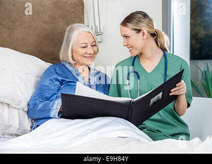 Pflegeperson zeigt medizinische Berichte zu Senior Woman Stockfoto