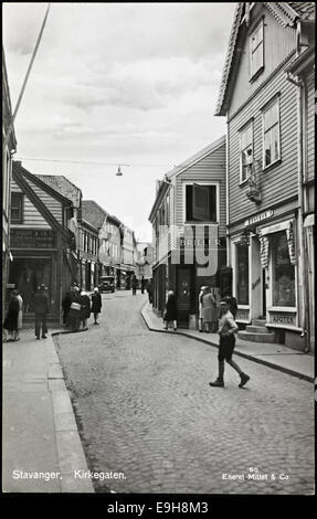 Eine historische Postkarte mit Kirkegaten in Stavanger, Norwegen. Das Bild fängt die lebendige Straßenszene mit Geschäften und Architektur ein, die typisch für Stavanger aus dem frühen 20. Jahrhundert in der Region Rogaland sind. Es wurde von Mittet & Co. Veröffentlicht. Harstad Kunstforlag und in der Nationalbibliothek von Norwegen aufbewahrt. Stockfoto