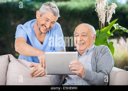 Krankenpfleger und Senior Mann lachen während der Verwendung von Digital-Tablette Stockfoto