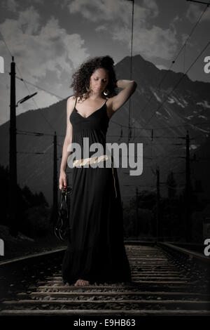 Frau in einem Kleid zu Fuß auf Eisenbahnschienen, Tirol, Österreich Stockfoto