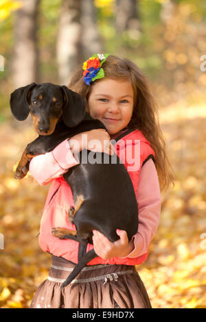 Kleines Kind mit einem Dackel-Welpen. Mädchen und Hund kuscheln Stockfoto