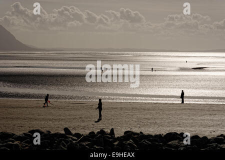 Glitzernde Meer am Westufer des Sees, Llandudno, Nordwales mit Menschen zu Fuß am Strand und genießen die Aussicht in Richtung Snowdonia. Stockfoto