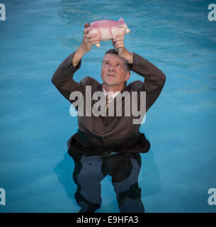 Senior woman Sparschwein über Wasser halten Stockfoto