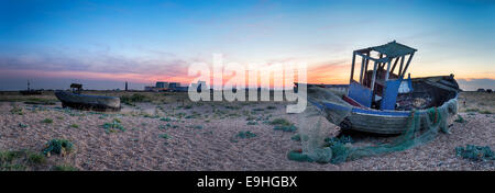 Ein altes zerstört Angelboote/Fischerboote bei Dungeness in Kent mit den zwei Leuchttürmen und Dungeness Kernkraftwerk im Hintergrund Stockfoto