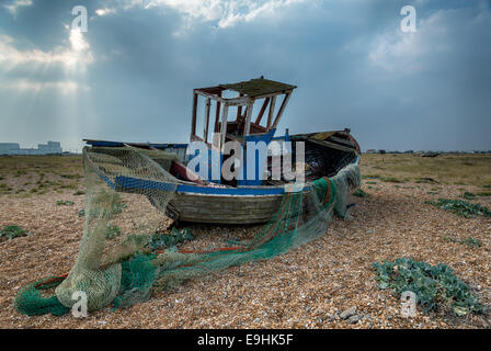 Alte hölzerne Angelboot/Fischerboot und Netze an einem Kiesstrand gestrandet Stockfoto