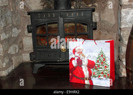 Weihnachtsgeschenk ein Santa Tasche vor der Holzofen Stockfoto