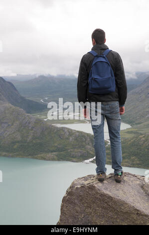 Junge Mann stand am Rande des Besseggen Bergrücken mit Blick auf Gjende-See und die umliegenden Berge. Norwegen. Stockfoto