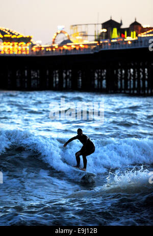 Brighton, Sussex, UK. 28 Oktober, macht 2014 A Surfer das Beste aus den Bedingungen unter den Lichtern der Brighton Pier im winter Stockfoto