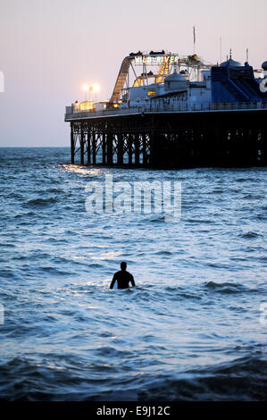 Brighton, Sussex, UK. 28 Oktober, macht 2014 A Surfer das Beste aus den Bedingungen unter den Lichtern der Brighton Pier im winter Stockfoto