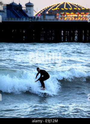 Brighton, Sussex, UK. 28 Oktober, macht 2014 A Surfer das Beste aus den Bedingungen unter den Lichtern der Brighton Pier im winter Stockfoto