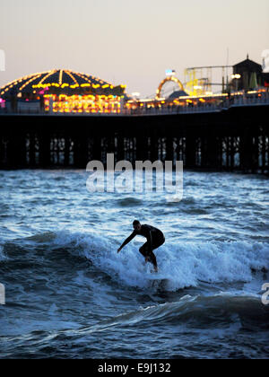 Brighton, Sussex, UK. 28 Oktober, macht 2014 A Surfer das Beste aus den Bedingungen unter den Lichtern der Brighton Pier im winter Stockfoto