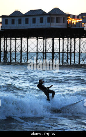 Brighton, Sussex, UK. 28 Oktober, macht 2014 A Surfer das Beste aus den Bedingungen unter den Lichtern der Brighton Pier im winter Stockfoto