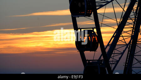 Sonnenuntergang hinter dem Rad of Excellence auf Brighton Seafront wie Menschen eine am frühen Abend Fahrt nach einem warmen sonnigen Tag nehmen Stockfoto