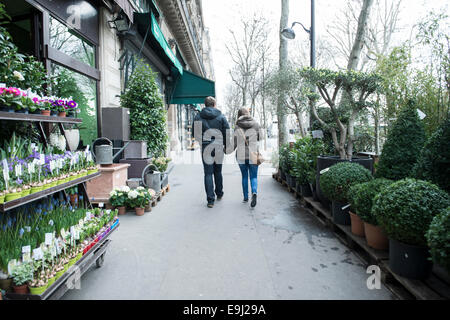 Eine Blume stall Anzeige auf den Straßen von Paris mit ein Paar in Liebe Hände halten vorbei gehen. Stockfoto