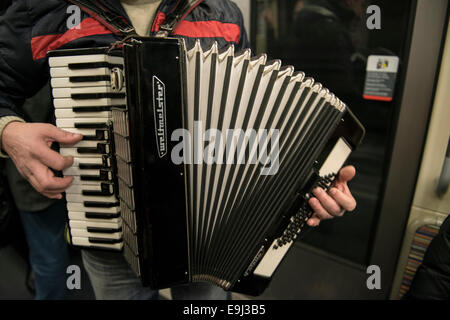 Ein Akkordeonspieler busks auf der Pariser Metro Züge mit einem traditionellen Blasinstrument Stockfoto