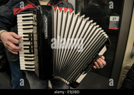 Ein Akkordeonspieler busks auf der Pariser Metro Züge mit einem traditionellen Blasinstrument Stockfoto